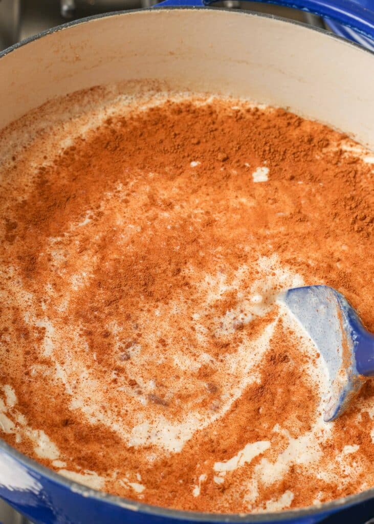 adding cinnamon to rice pudding in large pot
