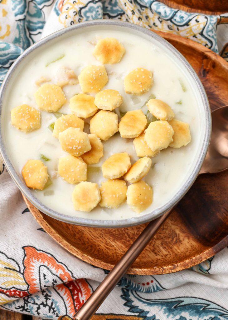 clam chowder topped with oyster crackers in pottery bowl on wooden plate