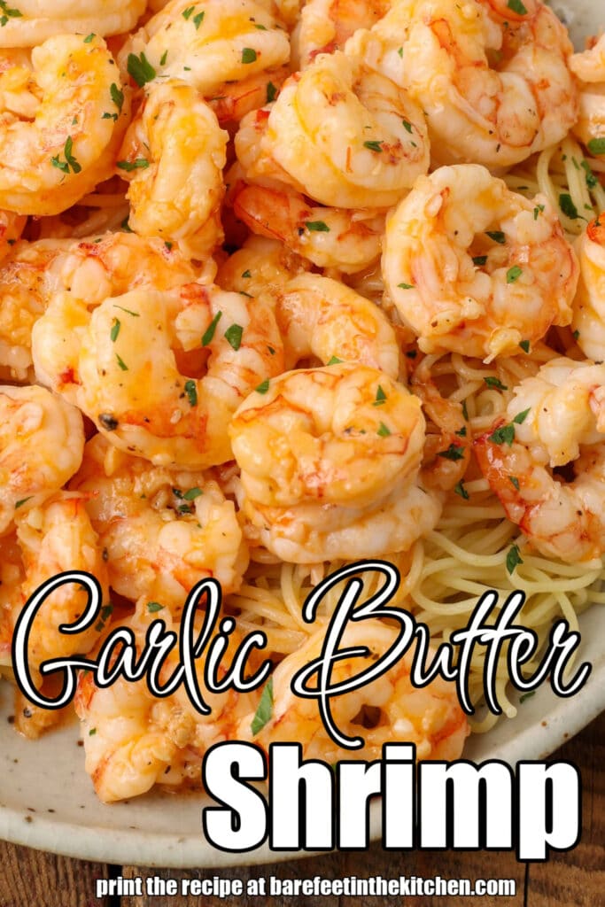 Garlic butter shrimp are piled high atop a white plate in this image that has been overlaid with white lettering. The lettering reads, "Garlic Butter Shrimp."