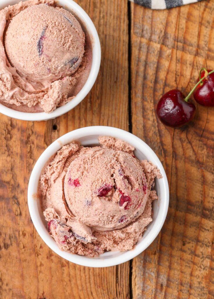 chocolate ice cream with roasted cherries in small white bowls on table