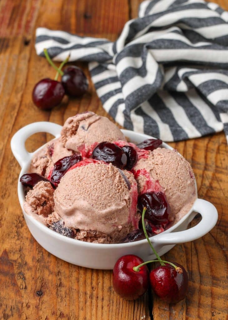 Chocolate Ice Cream with chopped cherries in white dish on wooden table