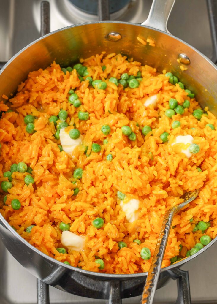 rice with turmeric, butter, and peas on stovetop